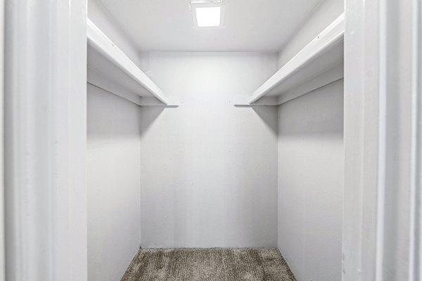 Walk-in closet with ample shelving space in Villatree Apartments bedroom