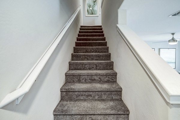Stairway with modern design at Town Surprise Townhome Apartments featuring sleek railings and natural light