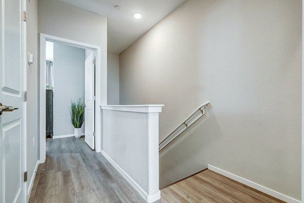 Hallway leading to stairway with modern lighting at Town Surprise Townhome Apartments