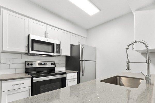 Modern kitchen with sleek appliances and quartz countertops in Verve Apartments
