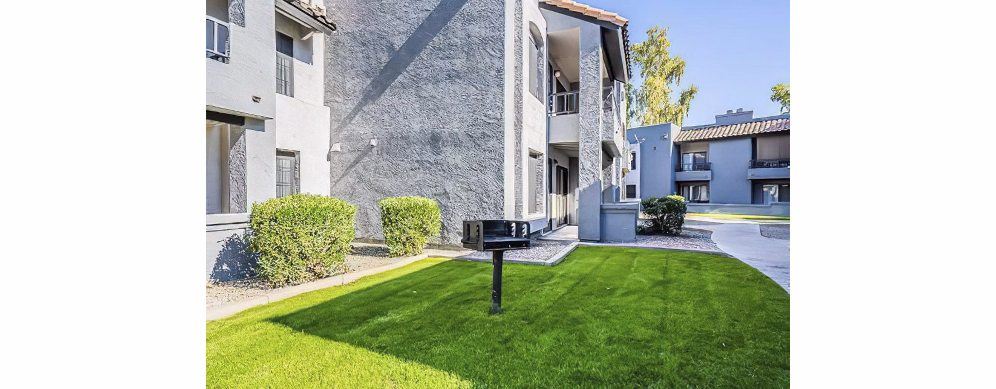 Outdoor grill area with seating and greenery at Verve Apartments