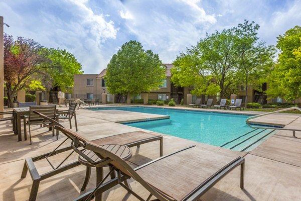 Outdoor pool with lounge chairs at Cinnamon Tree Apartments