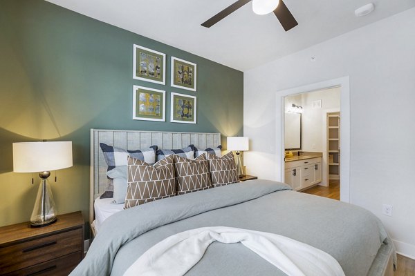 Sleek, modern bedroom with king-size bed and large windows at Elan Harvest Green Apartments, providing comfort and style