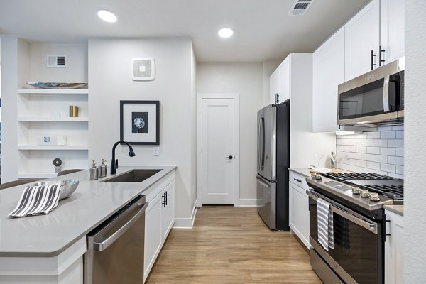 Modern kitchen featuring stainless steel appliances and granite countertops in Elan Harvest Green Apartments