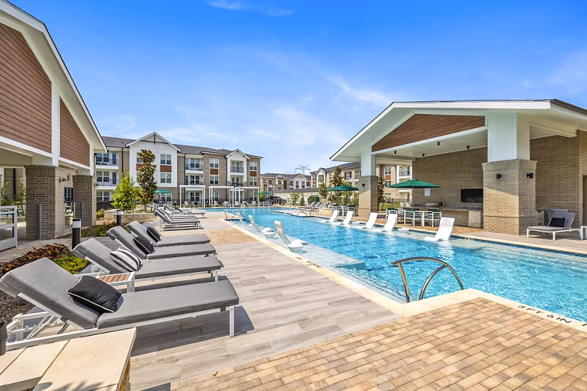 Modern lap pool at Elan Harvest Green Apartments featuring lush landscaping and poolside seating, perfect for relaxation and recreation