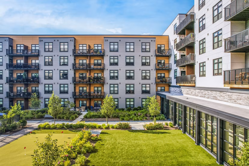 Modern luxury apartment building with balconies and landscaped courtyard in a vibrant community