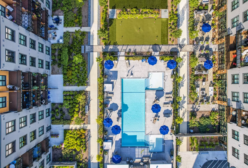 Aerial view of luxury apartments featuring a swimming pool and landscaped green spaces