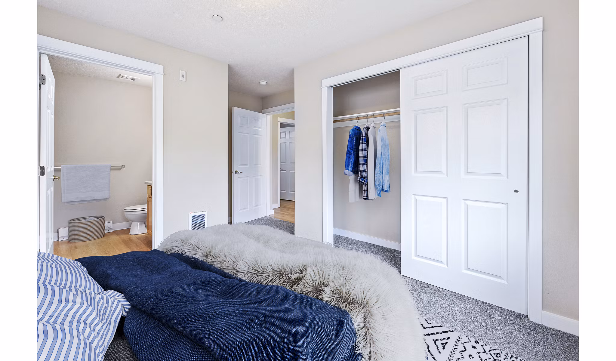 Cozy bedroom with modern furniture and large window at Trillium Apartments, offering luxury living in a serene setting