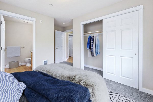 Cozy bedroom with modern furniture and large window at Trillium Apartments, offering luxury living in a serene setting