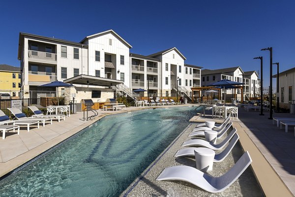 Resort-style pool at Austin Avenue Apartments featuring lush landscaping and ample lounge seating