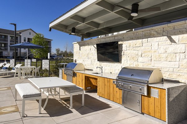 Grill area with modern seating at Austin Avenue Apartments, perfect for hosting gatherings and outdoor dining experiences