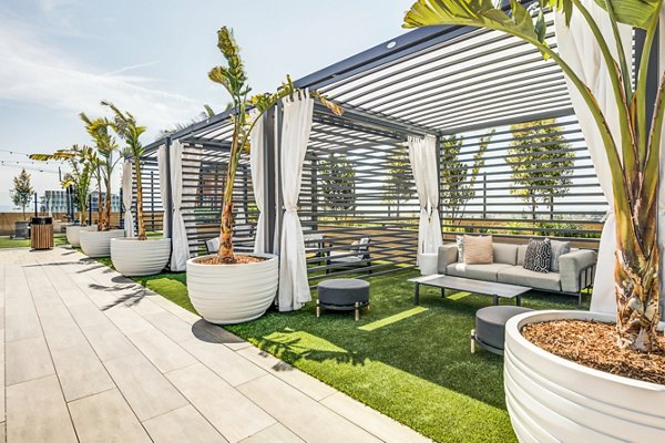 Modern pool patio with lounge chairs and umbrellas at Esperanza at Duarte Station Apartments, featuring luxury amenities