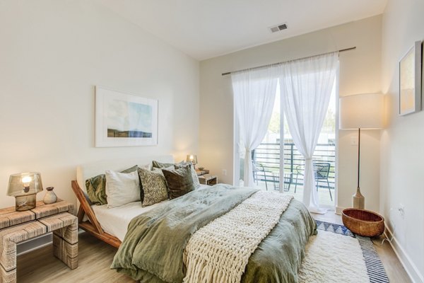 Cozy bedroom with modern decor at Centro Arlington Apartments, featuring plush bedding and ample natural light