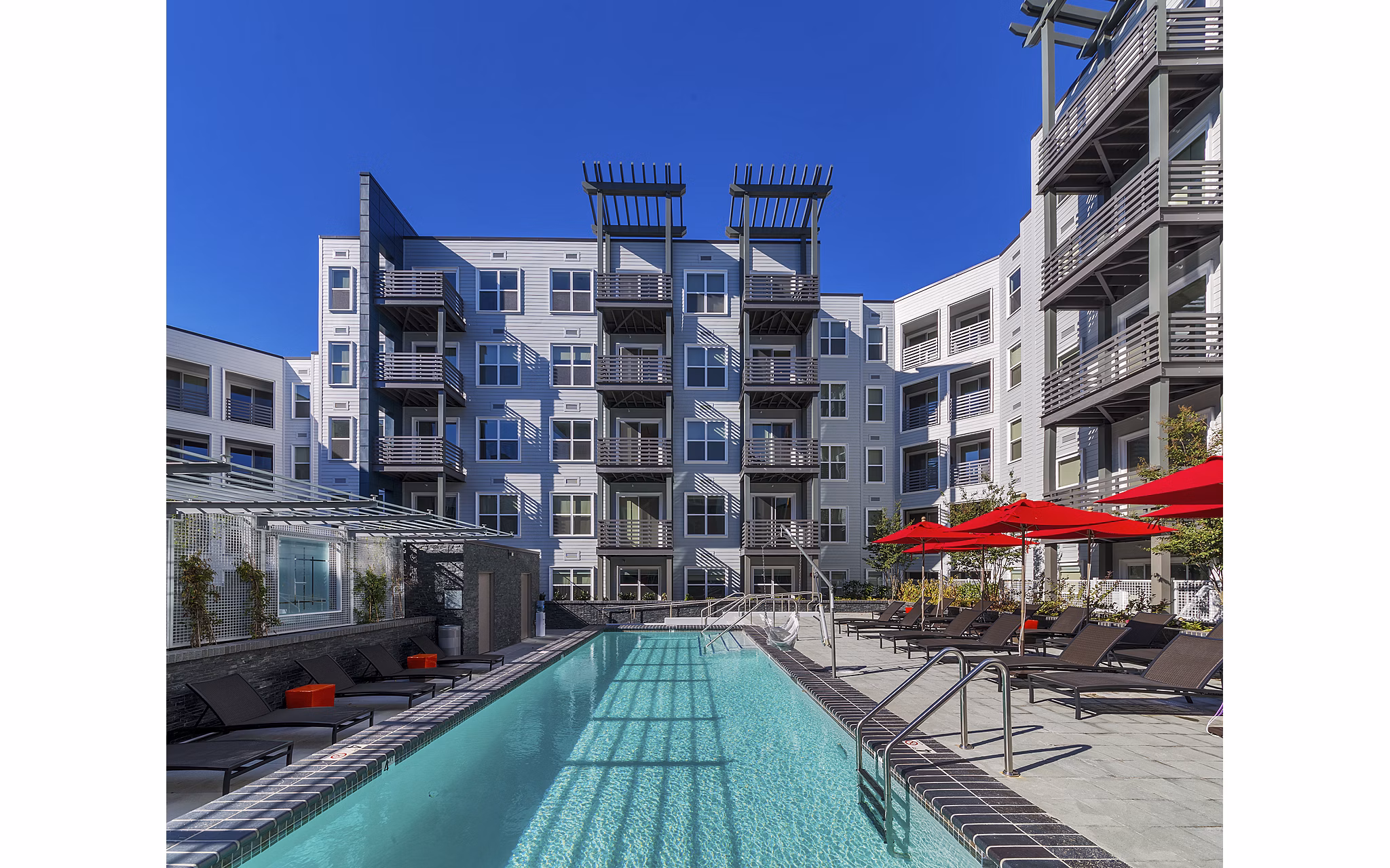 Sparkling outdoor pool at Notch8 Apartments with modern lounge chairs, offering luxury relaxation in the heart of vibrant city living