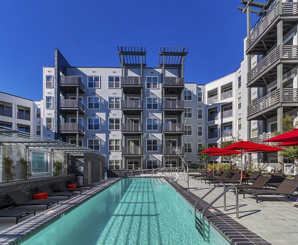 Sparkling outdoor pool at Notch8 Apartments with modern lounge chairs, offering luxury relaxation in the heart of vibrant city living