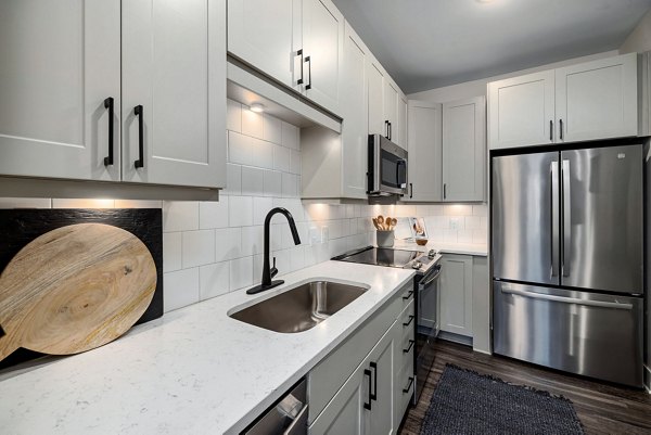 Modern kitchen with stainless steel appliances and granite countertops in The Signal Apartments, a luxury Greystar community