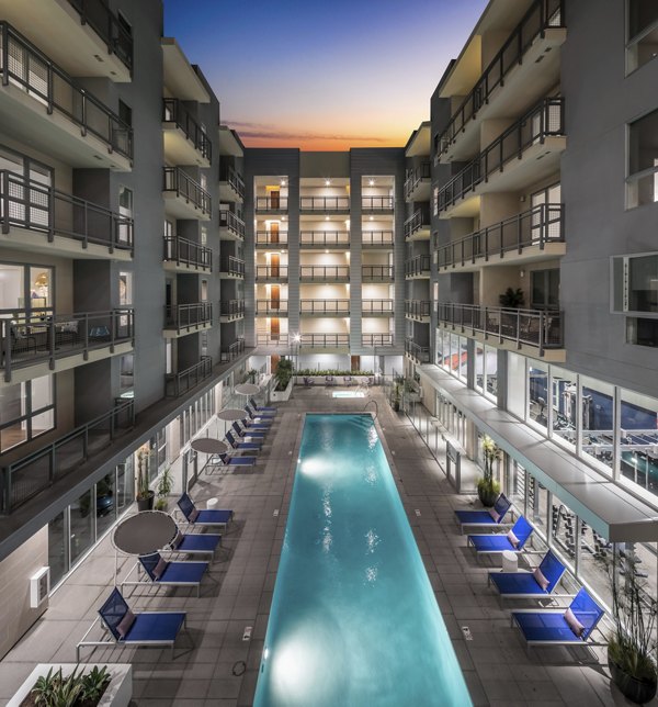 Modern outdoor pool at Next on Lex Apartments with lounge chairs and greenery backdrop