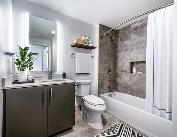 Modern bathroom with a sleek sink, spacious mirror, and a relaxing bathtub Natural accents from a plant on the counter