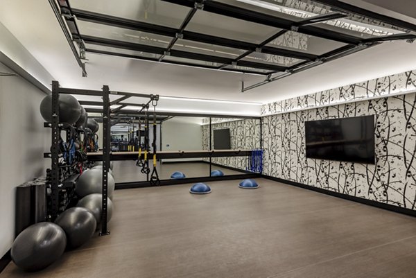 Fitness room featuring exercise equipment and a large mirror in luxury apartments