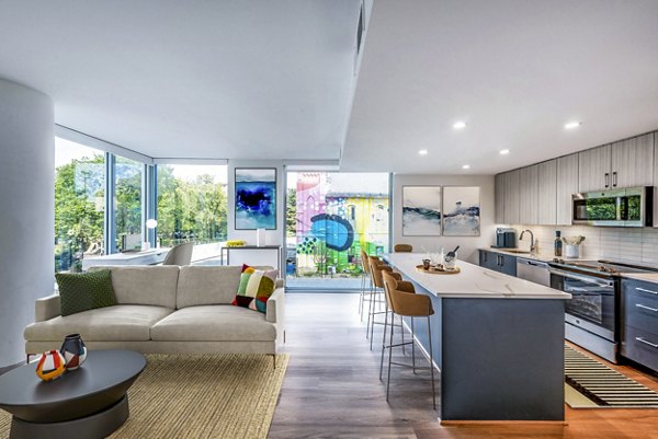 Open-concept living space with a modern kitchen island and bright dining area in luxury apartments