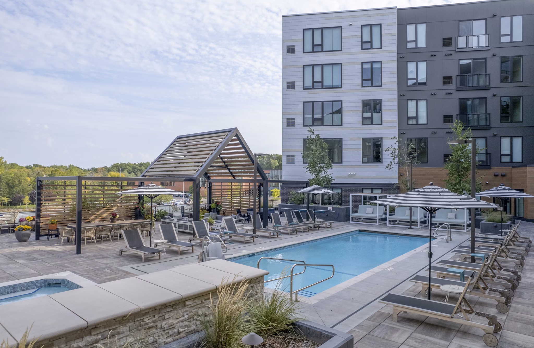 Luxurious outdoor pool at Avidor Minnetonka Apartments with comfortable lounge seating and lush landscaping