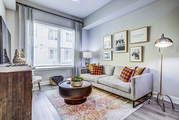 Modern living room with sleek furnishings in Zoey Apartments, featuring large windows for natural light