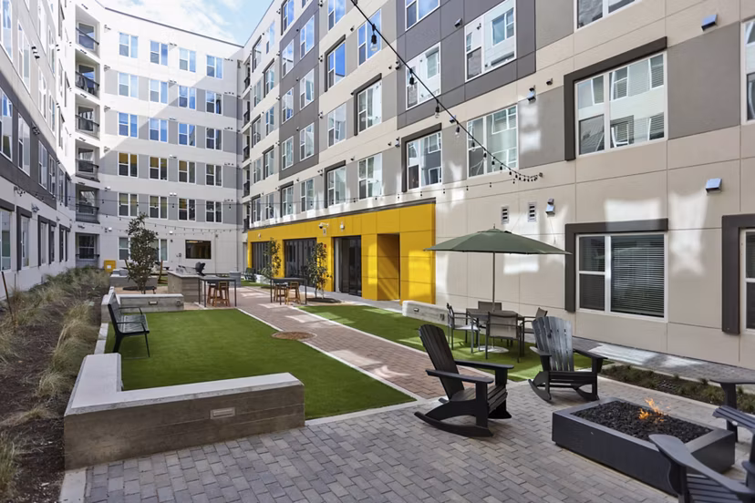 Zoey Apartments: Tranquil courtyard featuring lush greenery and seating areas in luxury apartment community