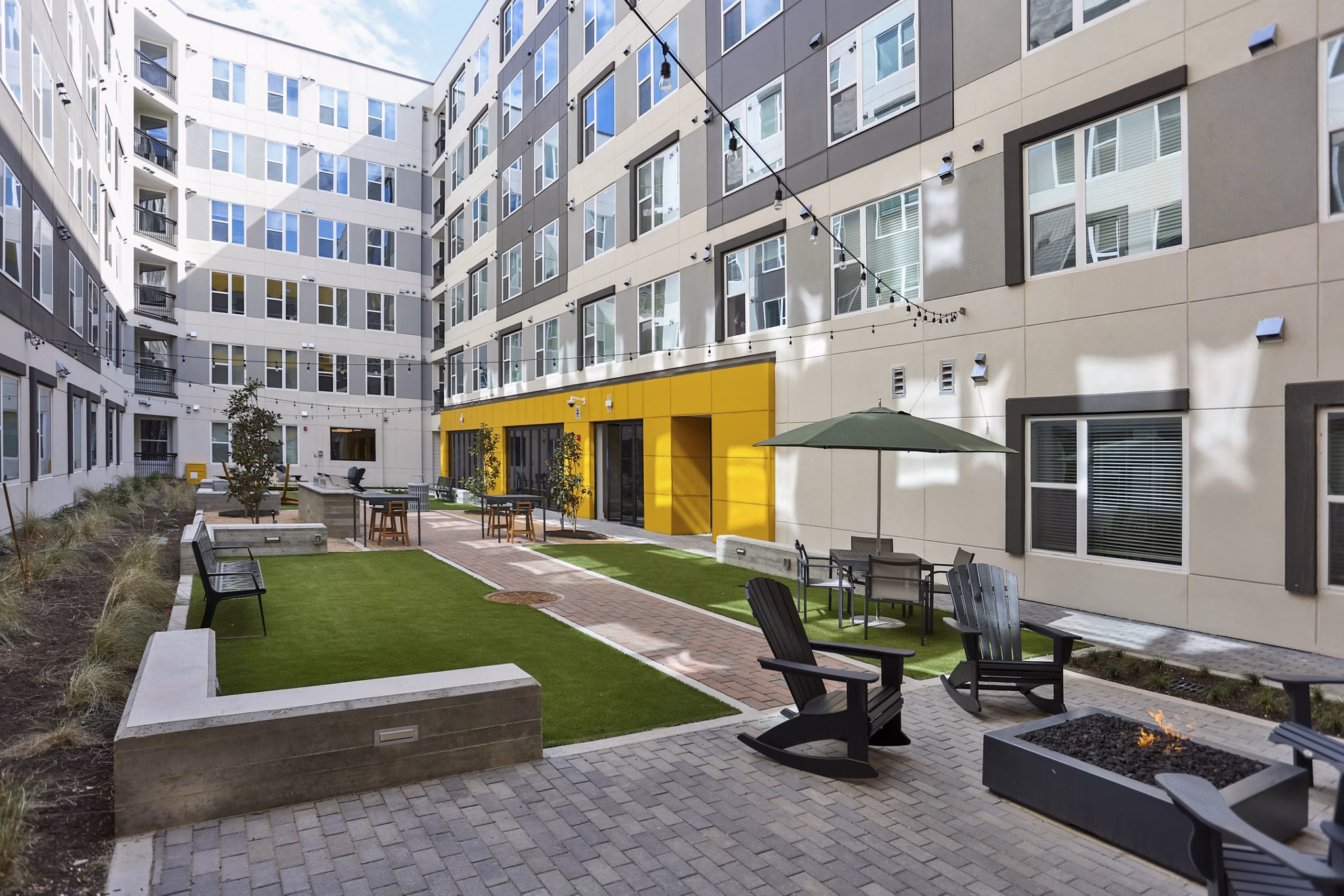 Zoey Apartments: Tranquil courtyard featuring lush greenery and seating areas in luxury apartment community