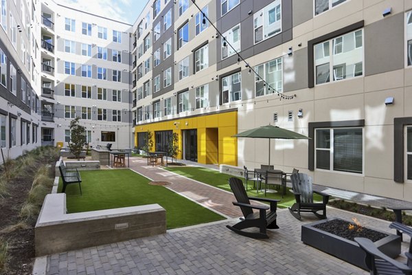 Zoey Apartments: Tranquil courtyard featuring lush greenery and seating areas in luxury apartment community