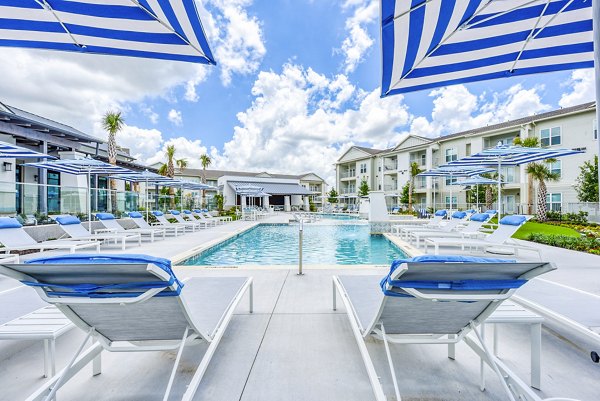 Resort-style pool at Tacara Dove Creek Apartments with palm trees and lounge chairs