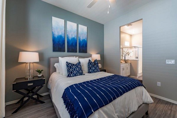 Cozy bedroom with modern decor at Vlux at Sunset Farms Apartments, offering luxury living in a serene environment