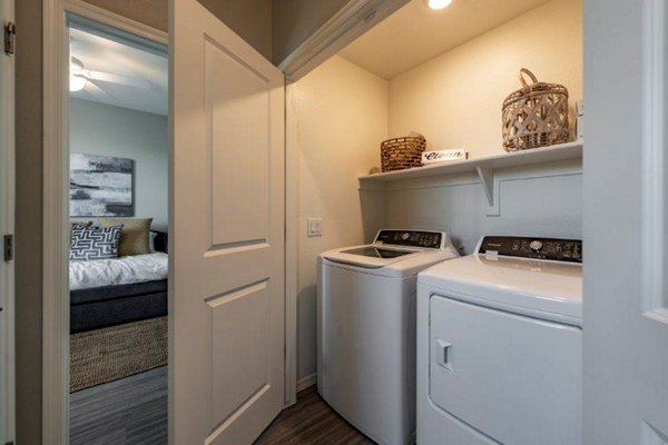 Laundry room with modern washers and dryers at Vlux at Sunset Farms Apartments in a Greystar-managed community