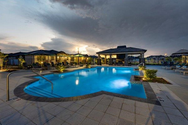Relaxing pool with lounge chairs at Vlux at Sunset Farms Apartments, a Greystar luxury community