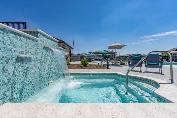 Luxurious pool area at Vlux at Sunset Farms Apartments with modern lounge seating and palm trees, offering a relaxing retreat for residents