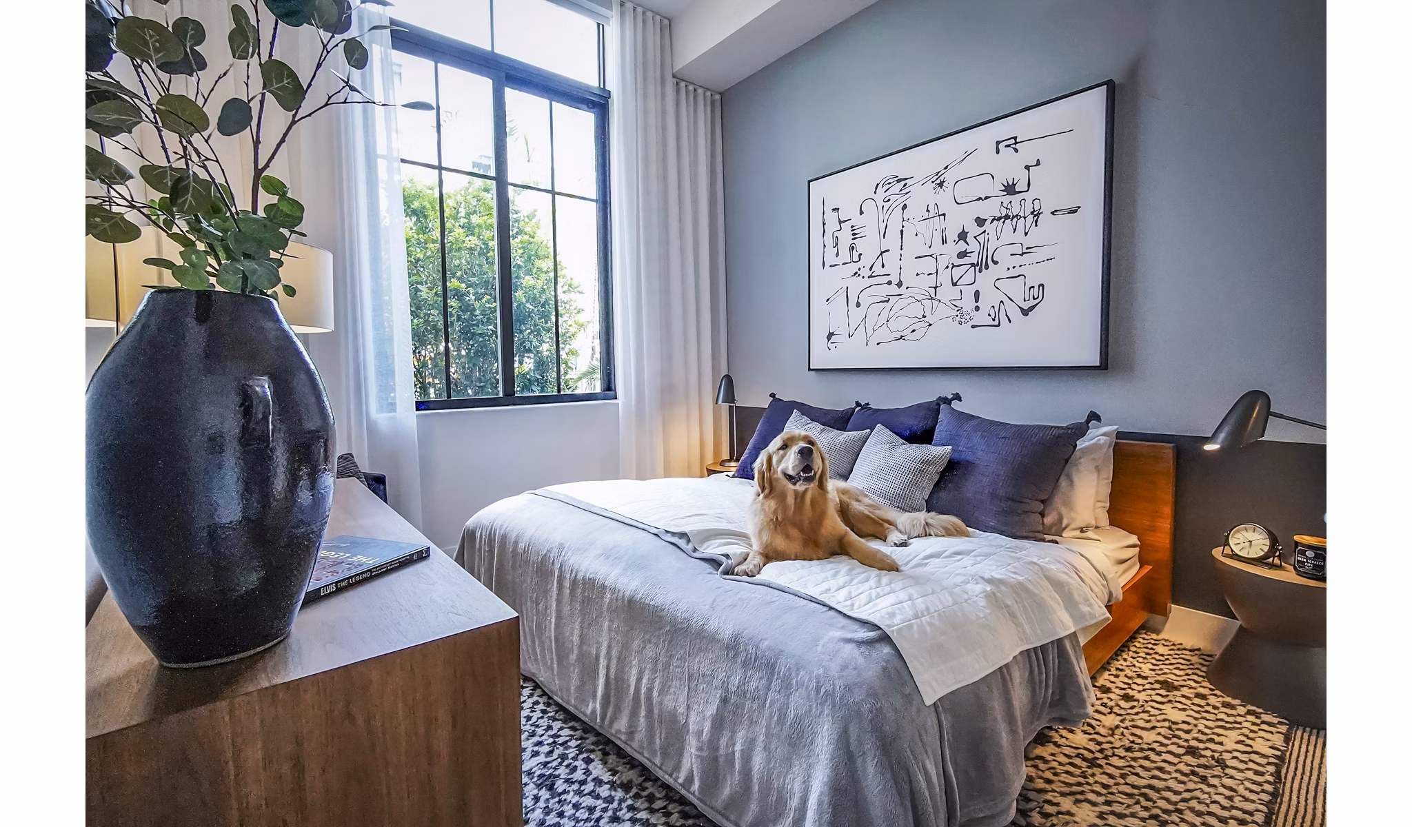 Cozy bedroom with modern decor at The Ellsworth Apartments, featuring plush bedding and ample natural light