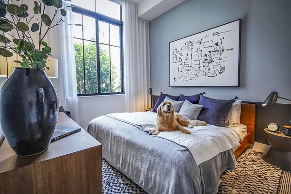 Cozy bedroom with modern decor at The Ellsworth Apartments, featuring plush bedding and ample natural light