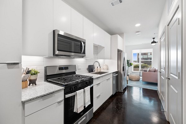Modern kitchen with quartz countertops and stainless steel appliances at The Oliver Apartments