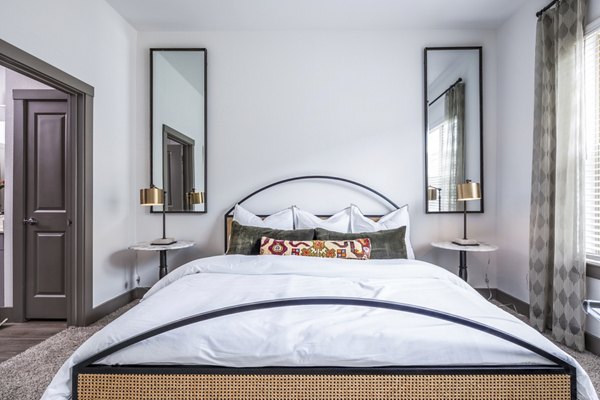 Cozy bedroom featuring a stylish bed, two mirrors, and bedside tables with lamps in luxury apartment