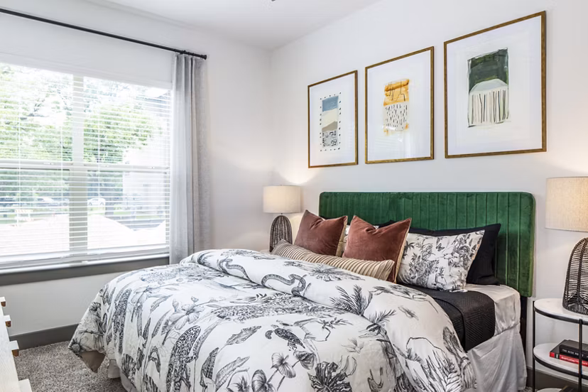 Spacious bedroom with decorative pillows and framed artwork in luxury apartment