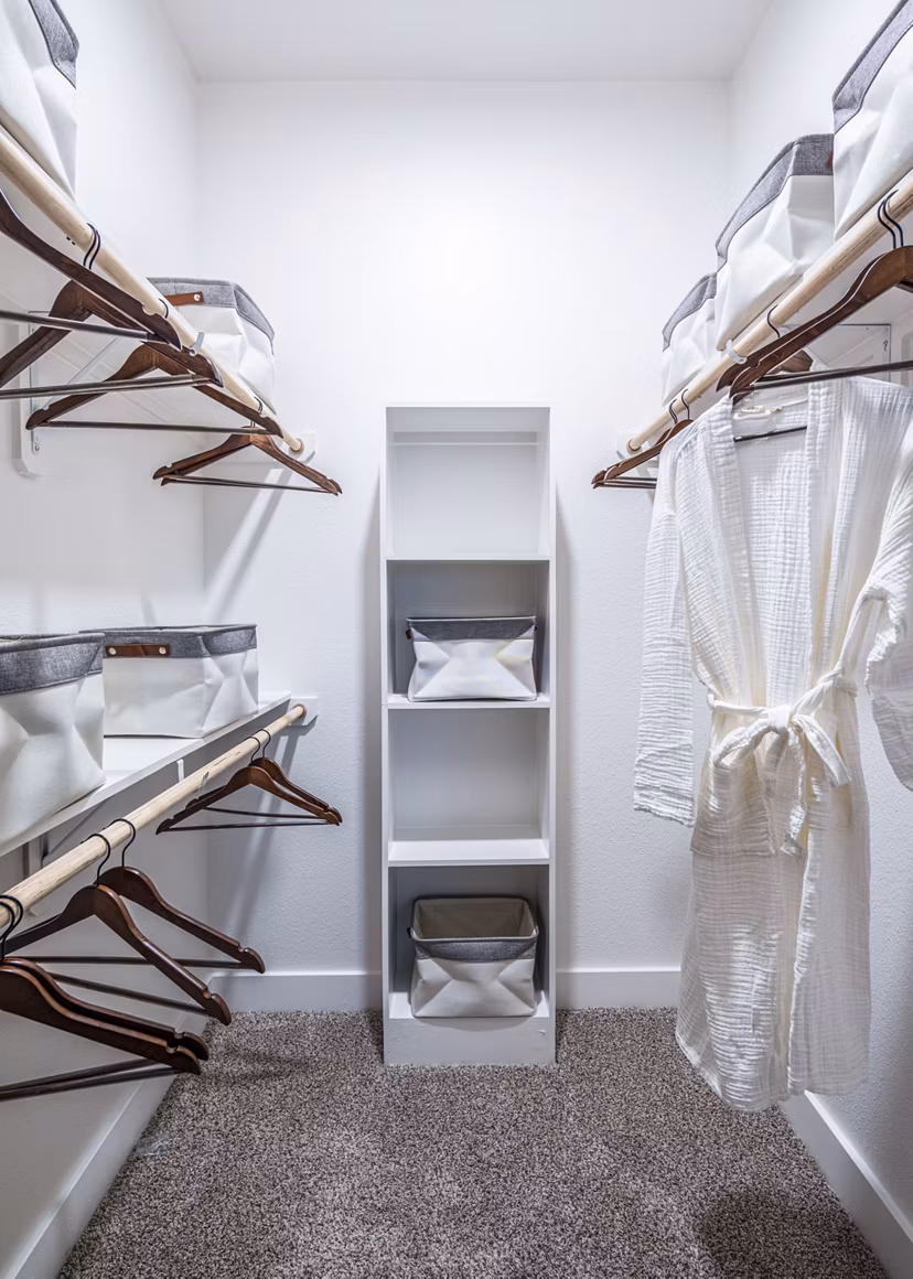Spacious walk-in closet with organized shelves and a white robe in luxury apartments