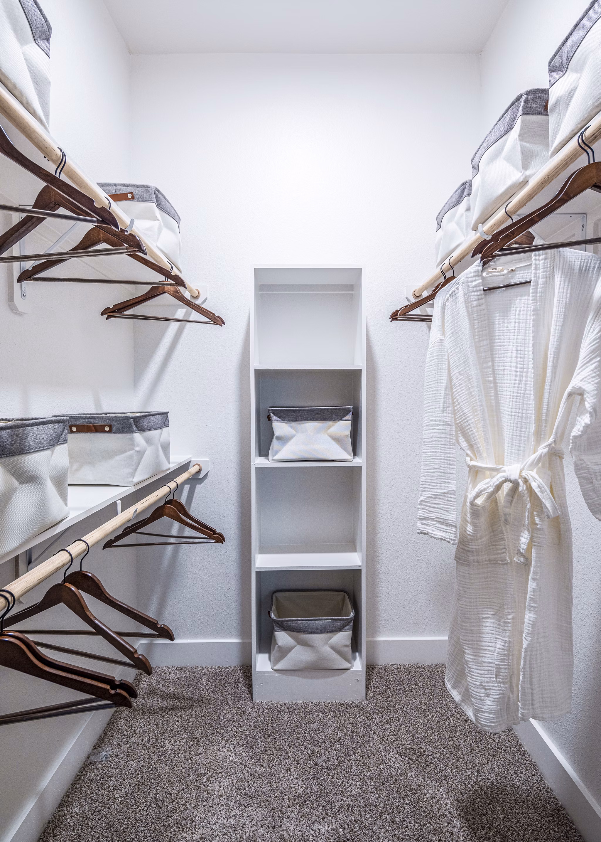 Spacious walk-in closet with organized shelves and a white robe in luxury apartments
