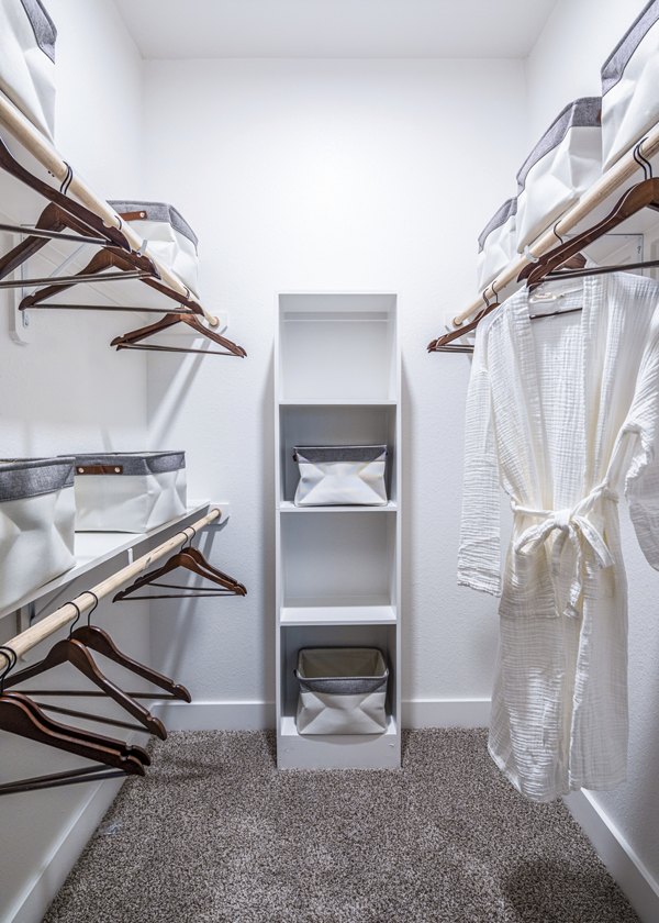 Spacious walk-in closet with organized shelves and a white robe in luxury apartments