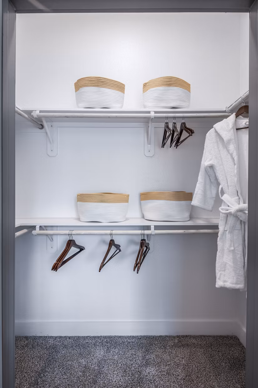 Spacious closet with shelves and hanging space featuring white robe and stylish baskets