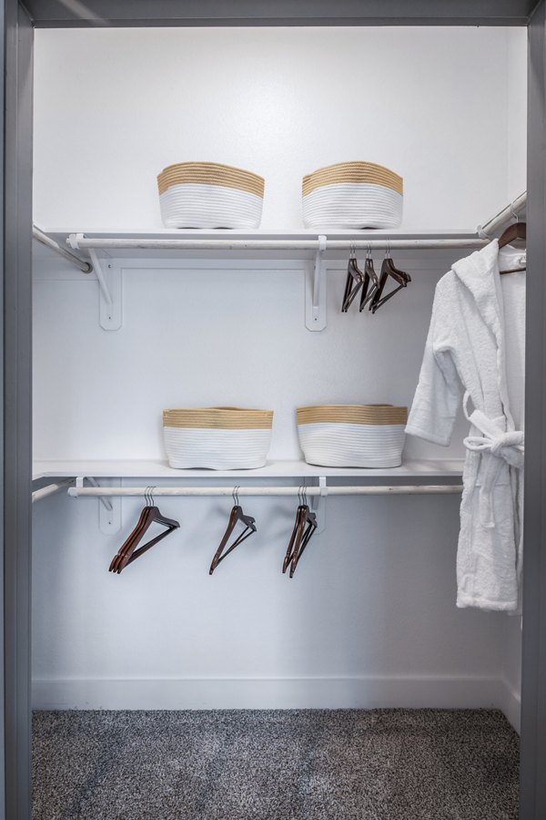 Spacious closet with shelves and hanging space featuring white robe and stylish baskets