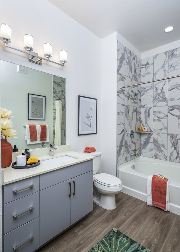 Modern bathroom featuring a sink, mirror, toilet, and bathtub in luxury apartments