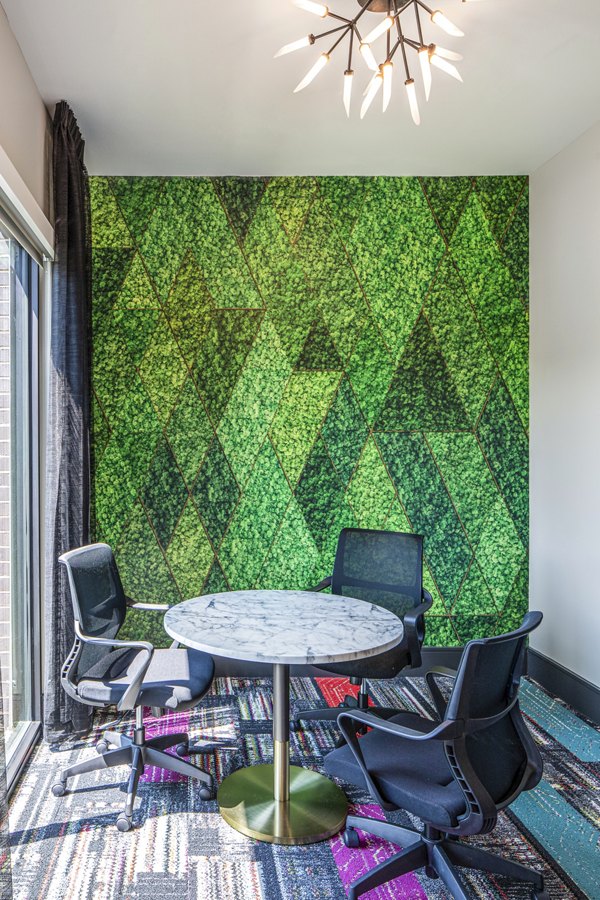 Cozy meeting room with a round marble table and three black chairs, featuring a green geometric patterned wall