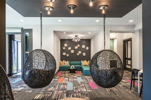 Modern living room featuring hanging chairs, a colorful carpet, and a green sofa in luxury apartments