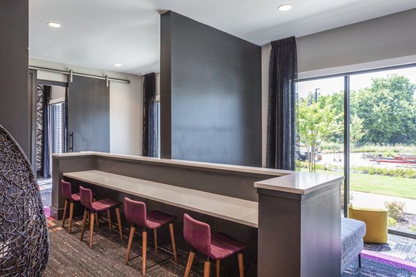 â€œModern dining area with a long table and purple chairs, showcasing large windows and views of lush greeneryâ€
