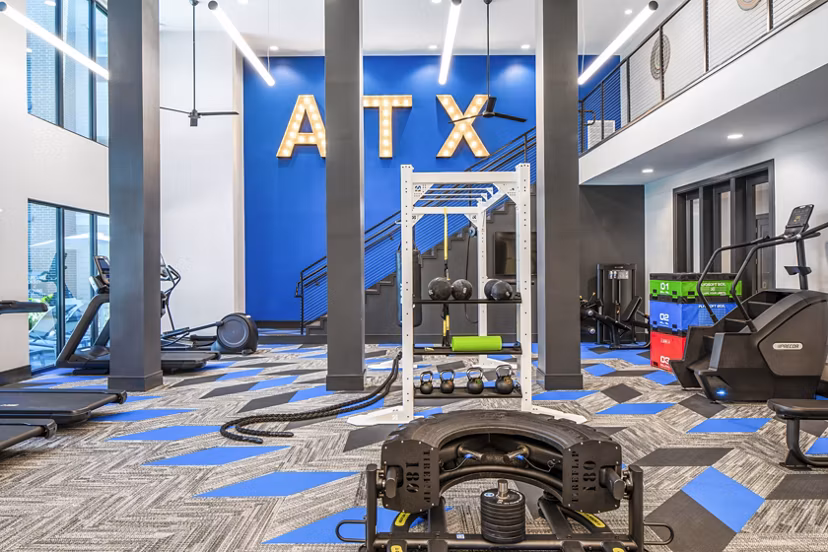 Modern gym featuring exercise equipment and ATX wall art at luxury apartments