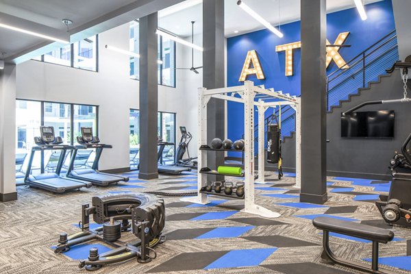 Modern gym featuring exercise equipment, including treadmills and weights, with ATX displayed on the wall